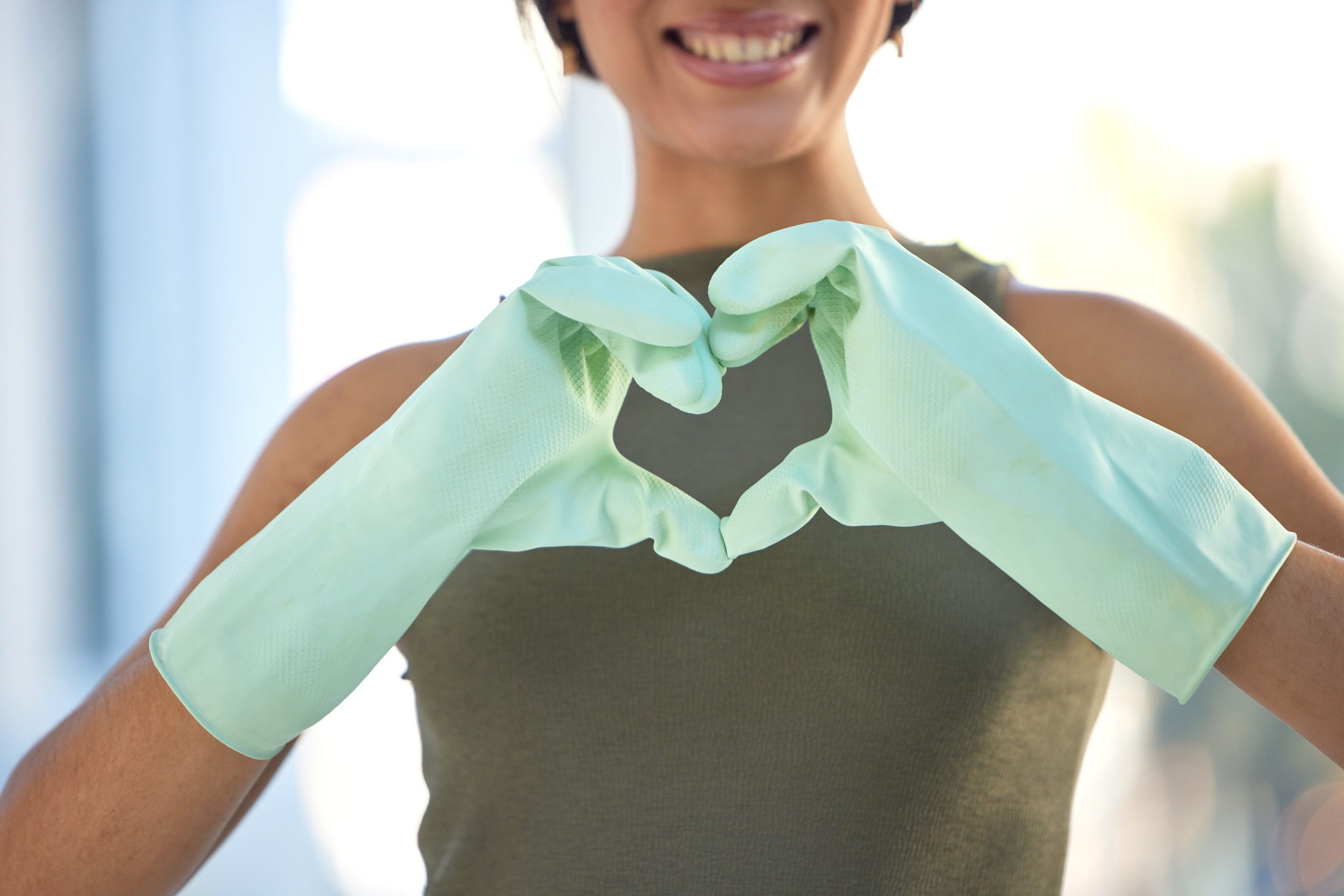 donna che fa un cuore con le mani coperte da guanti
